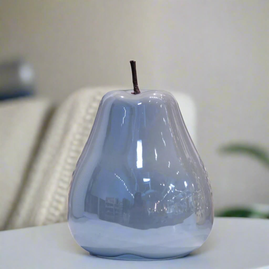 Glossy pear-shaped object on a table with a blurred background