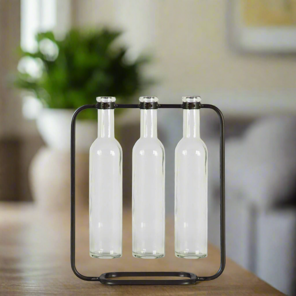 Three clear bottles in a black holder on a wooden surface with a blurred background