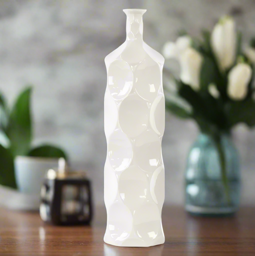 White textured vase on a wooden surface with a blurred background