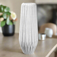 White textured vase on a table with a blurred background