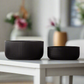 Two black textured bowls on a white table with a blurred background
