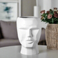 White vase shaped like a face on a white background