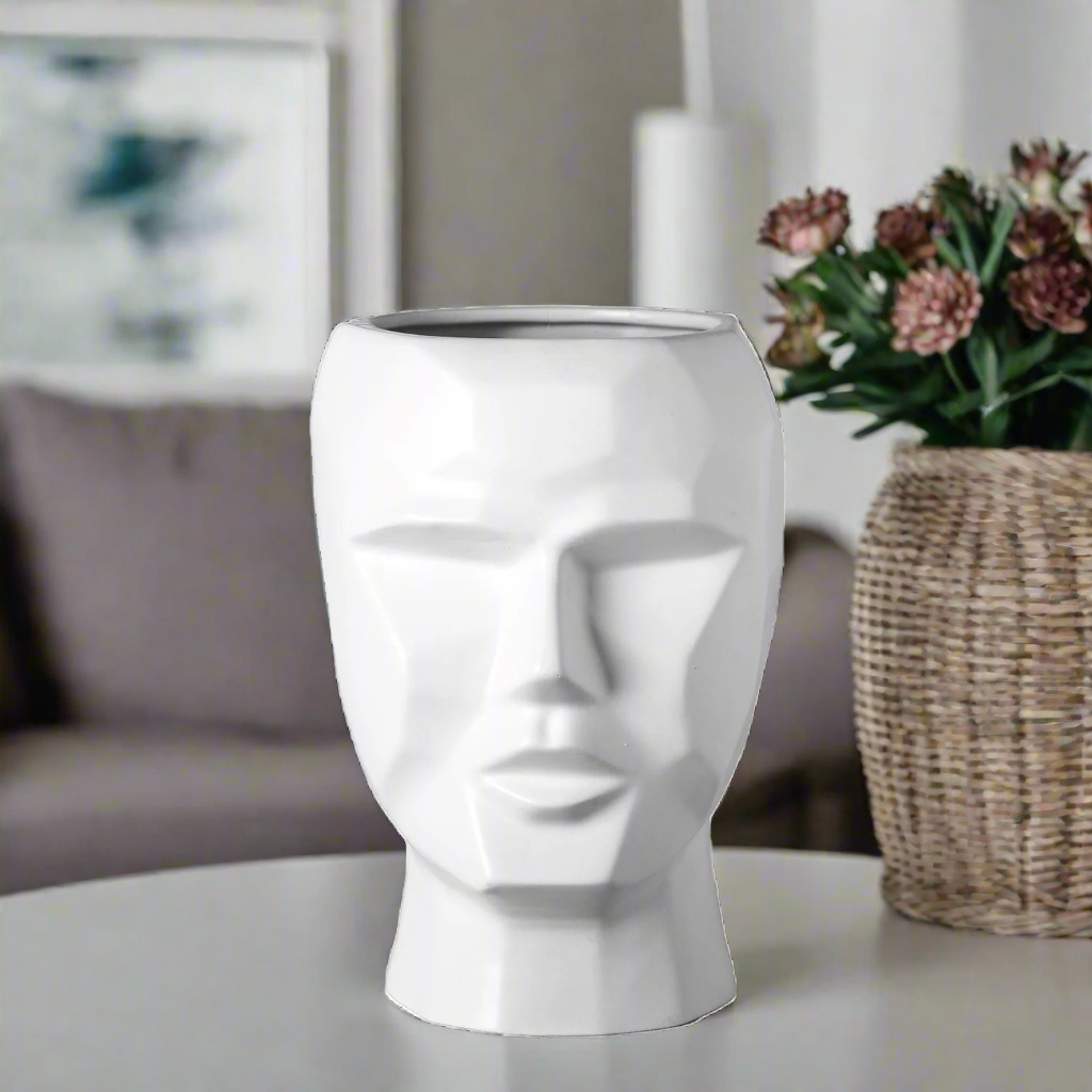 White vase shaped like a face on a white background