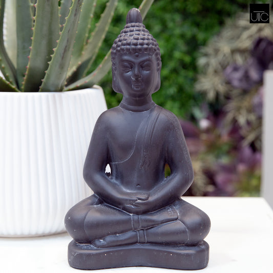 A terracotta Buddha figurine in a weathered finish, displayed in a garden setting.