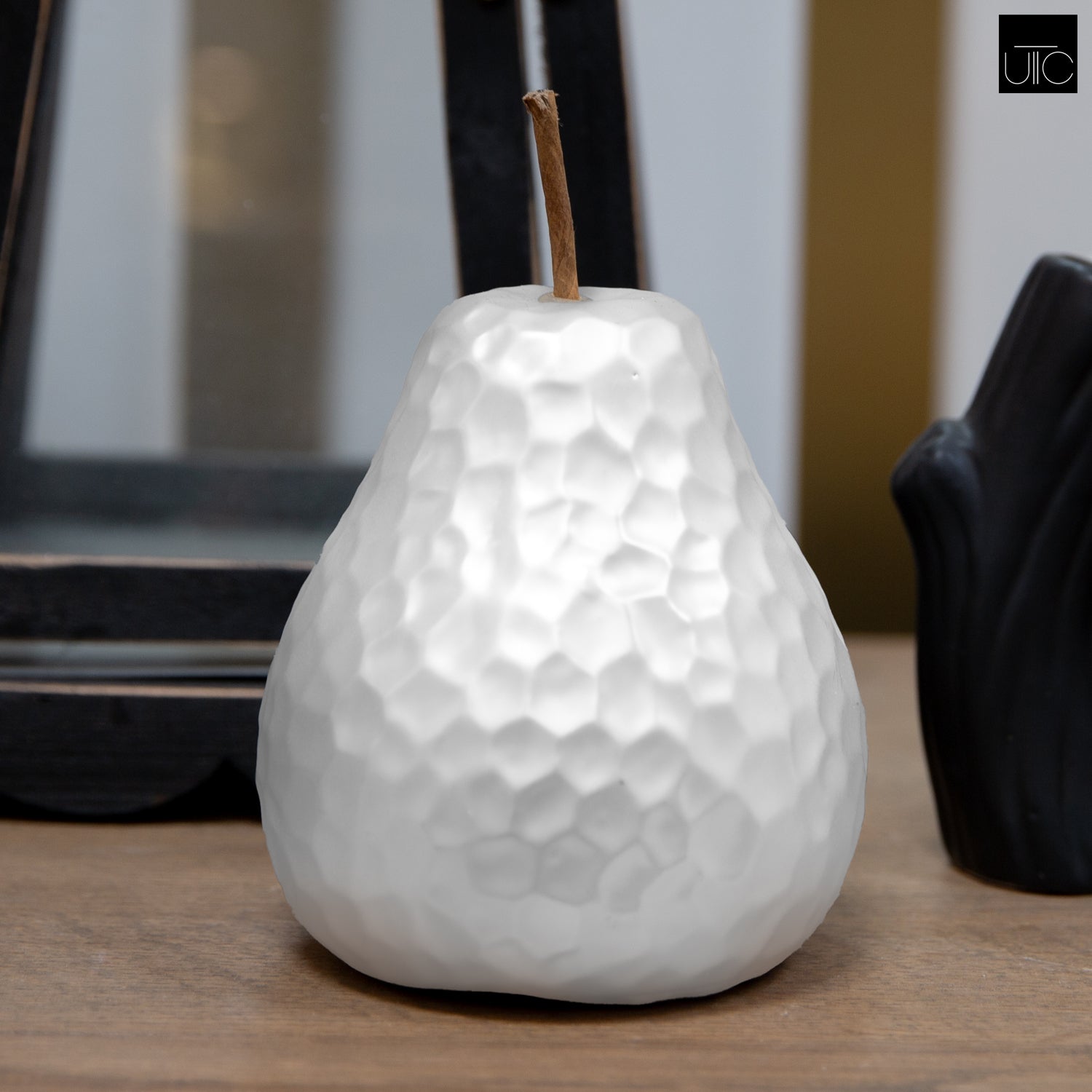 White textured pear-shaped candle on a table.