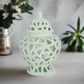 Decorative light green lantern with intricate lattice design on a neutral background