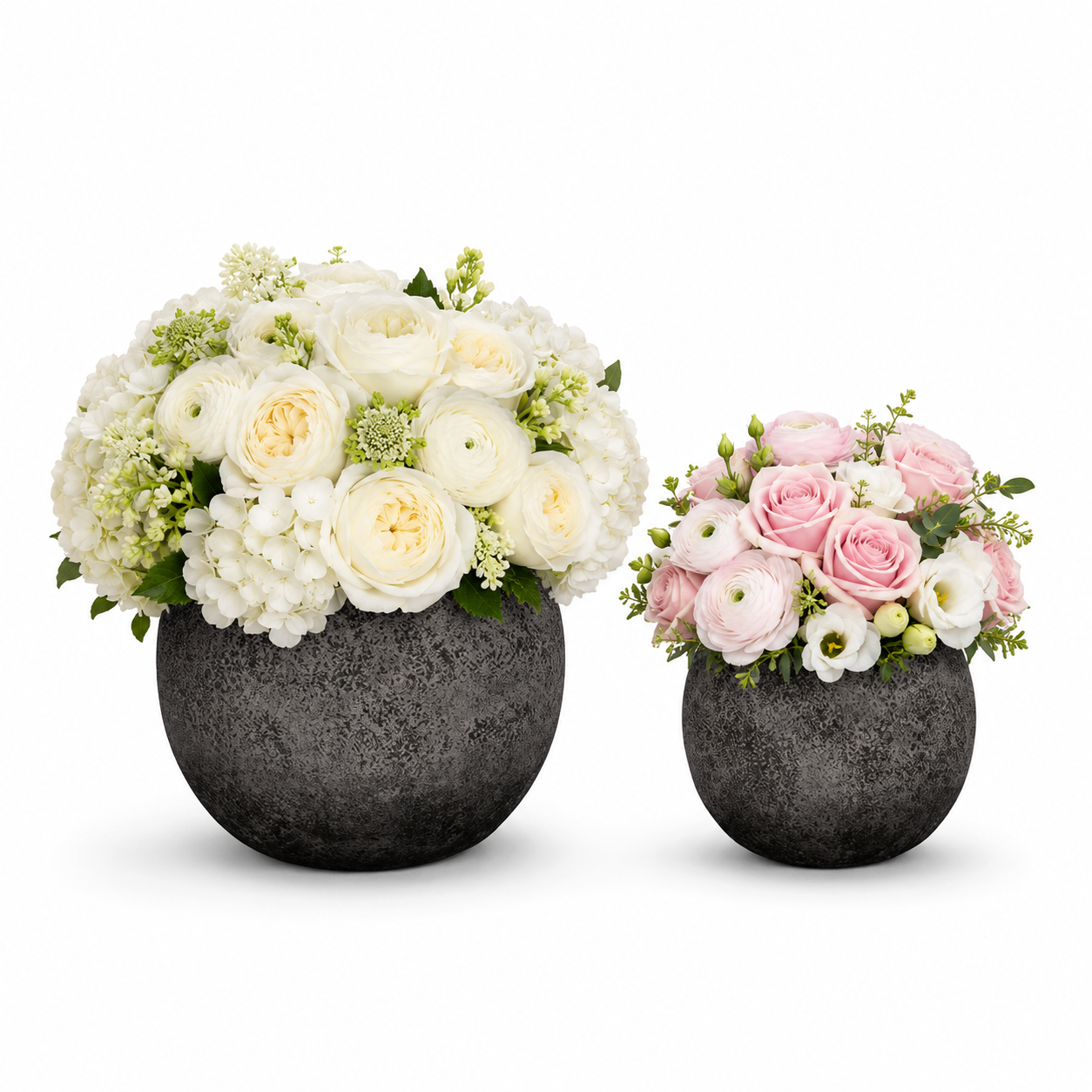 Two round dark gray stone flower vases on a white background, one holding a large bouquet of white and cream roses and hydrangeas, and the other holding a smaller bouquet of pink and white roses and ranunculus.