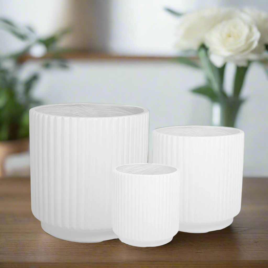 Set of three white ribbed planters on a wooden surface with a blurred background