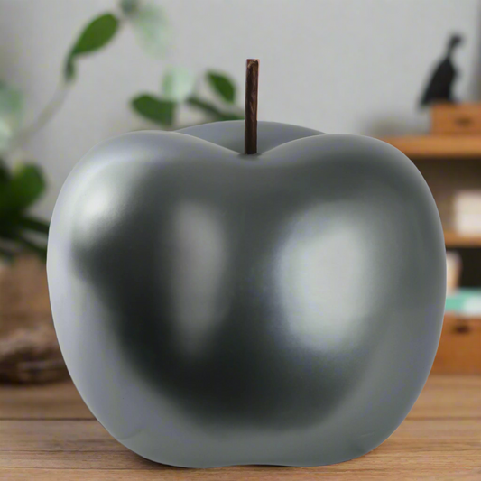 Gray apple-shaped object on a wooden surface with a blurred background