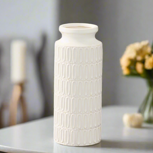 White textured vase on a table with a blurred background