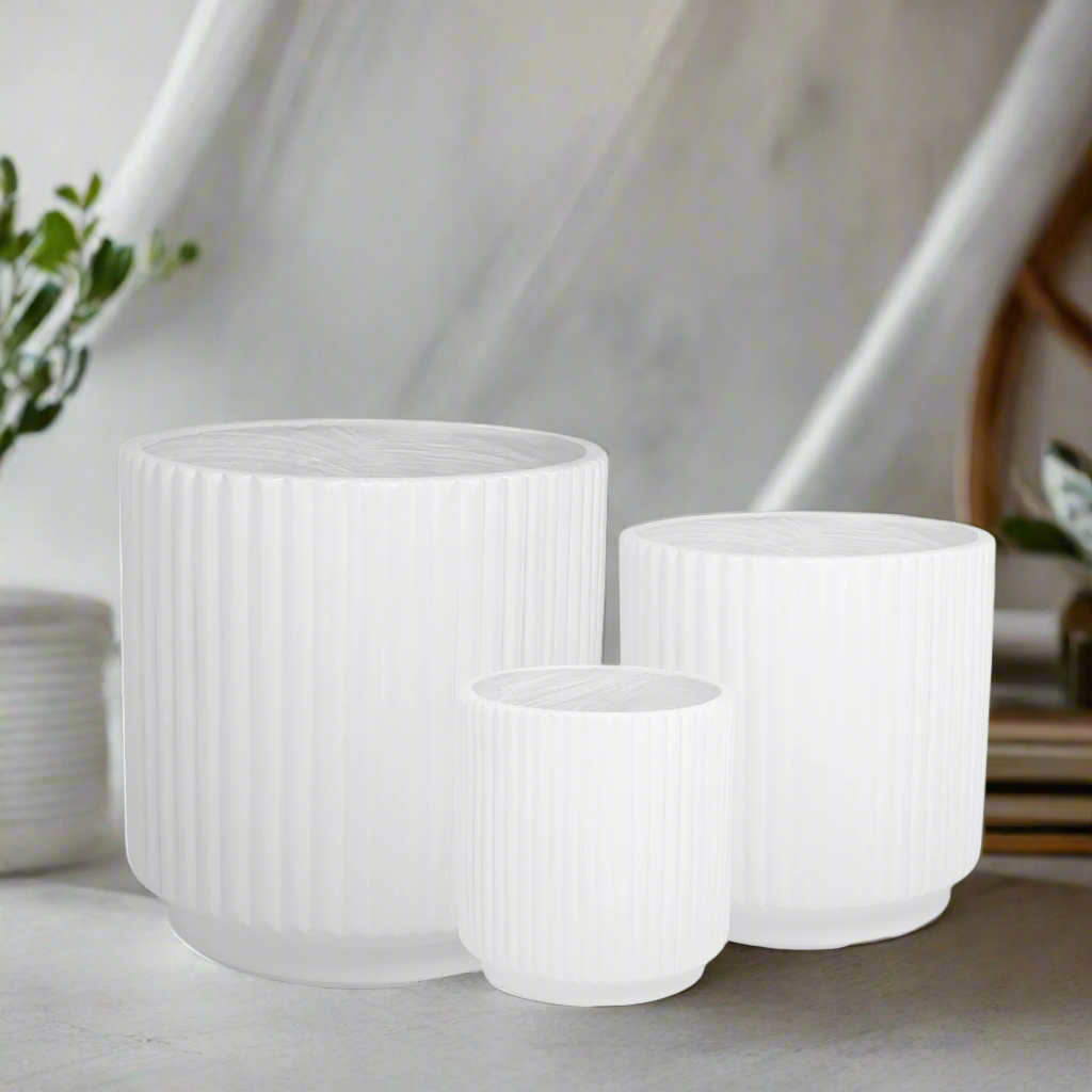 Three white textured planters on a light surface with a blurred background