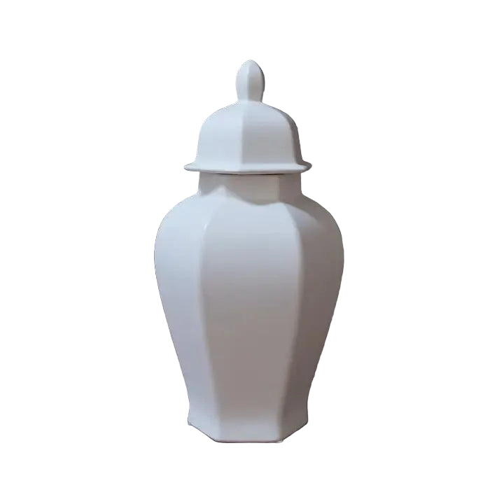 A white ceramic lidded jar or canister with a pointed finial top, shown on a wooden surface against a dark brick wall. White measurement lines and text indicate a height of 17.