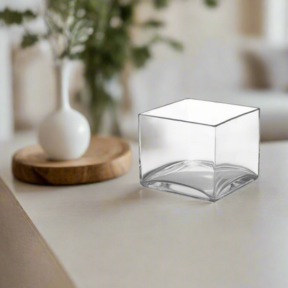 Clear glass cube on a white surface with a blurred background